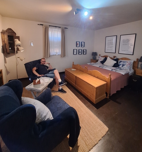 Cozy guest room with a man sitting in a chair.