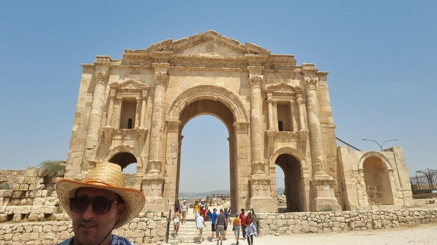 Arch of Hadrian in Jerash, with people walking around.