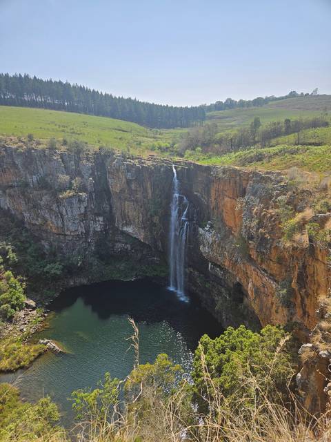 Tall waterfall surrounded by lush vegetation.
