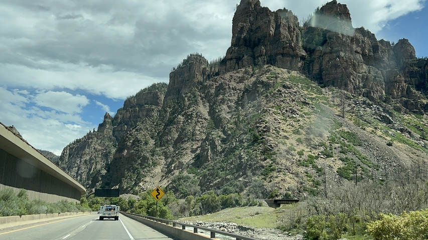      Scenic view of cliffs alongside a road with vehicles.
  