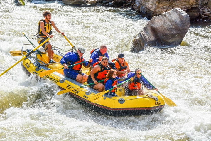       Group white-water rafting on a river with rocks and rapids.
  