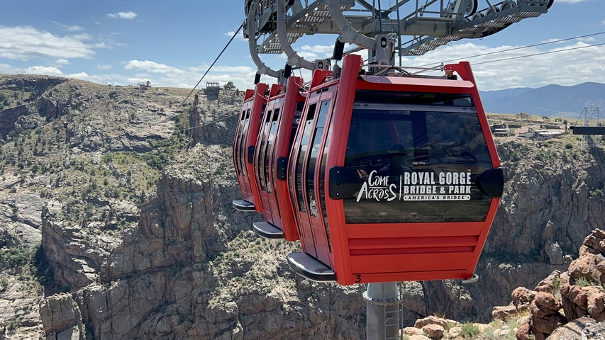       Cable car gondolas with a canyon background.
  