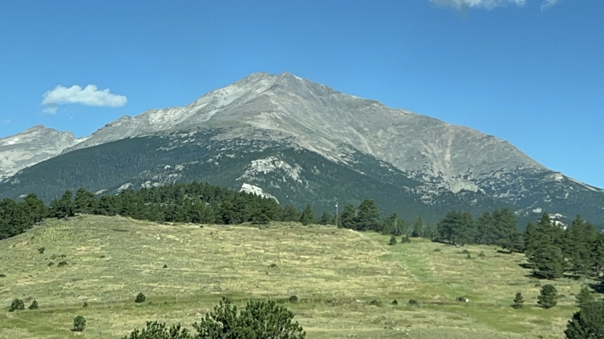       Distant mountain peak with a clear blue sky and forested foreground.
  