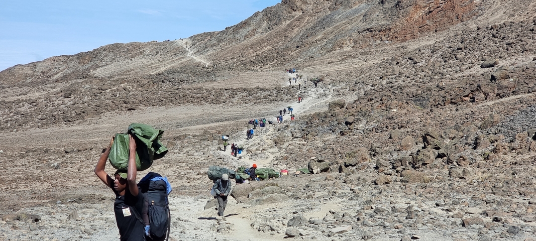 People hiking along a rocky trail in the mountains.