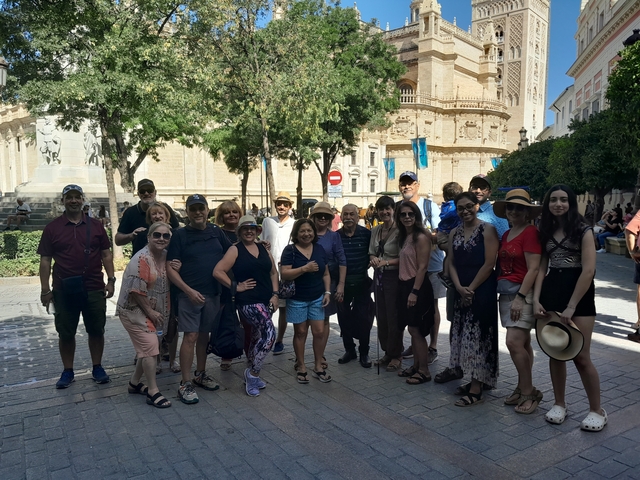 A large group of tourists posing in front of a historical building.