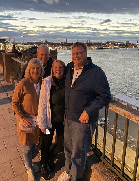 Four people posing near a waterfront with sunset lighting.
