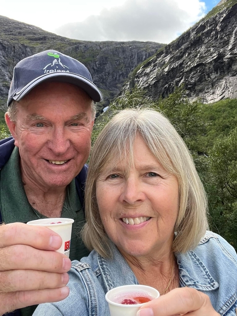 A couple smiling with a lush green background.