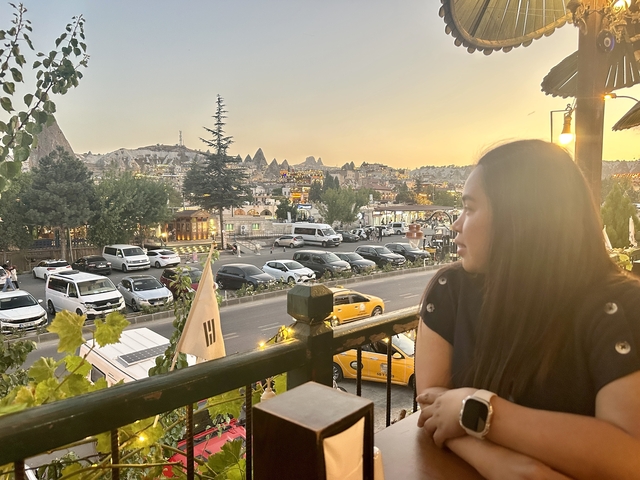       Woman enjoying a view of a town at sunset.
  