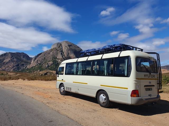       Tour bus parked near a mountain range.
  