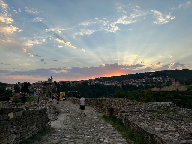 Group of people walking along a historic stone path at sunset.