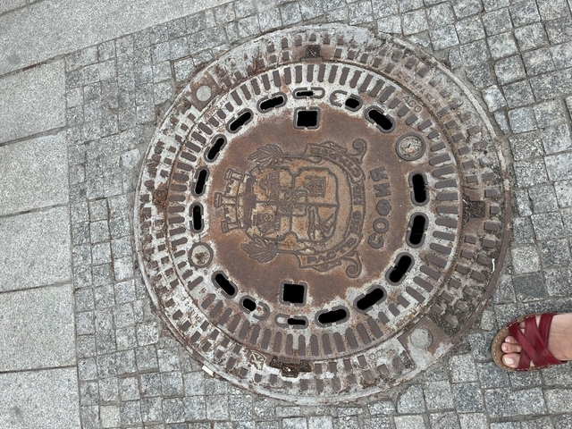 Rusty manhole cover with inscriptions.