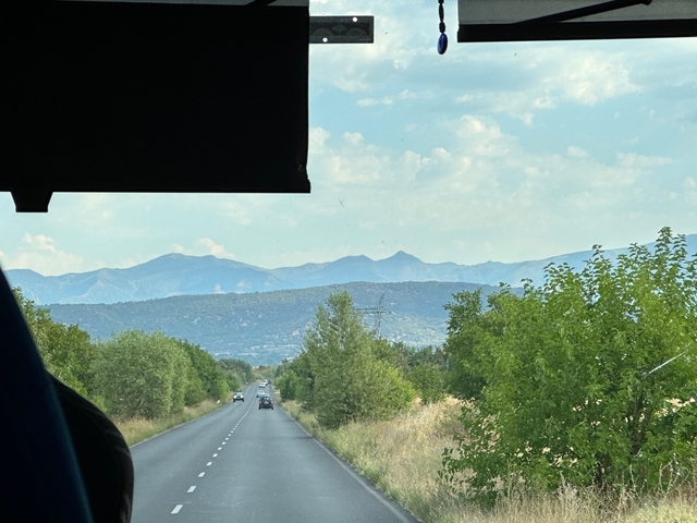 View of a mountain road from inside a vehicle.