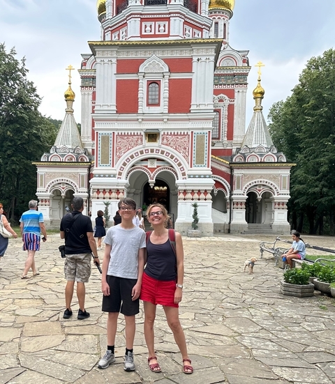 Group of tourists posing in front of a colorful church.