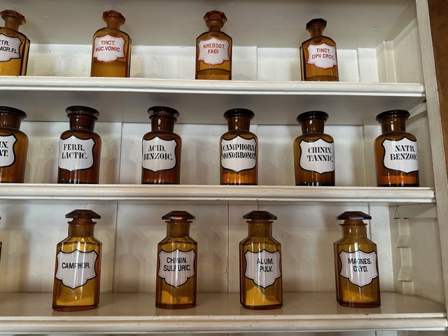 Old glass bottles lined up on a shelf.