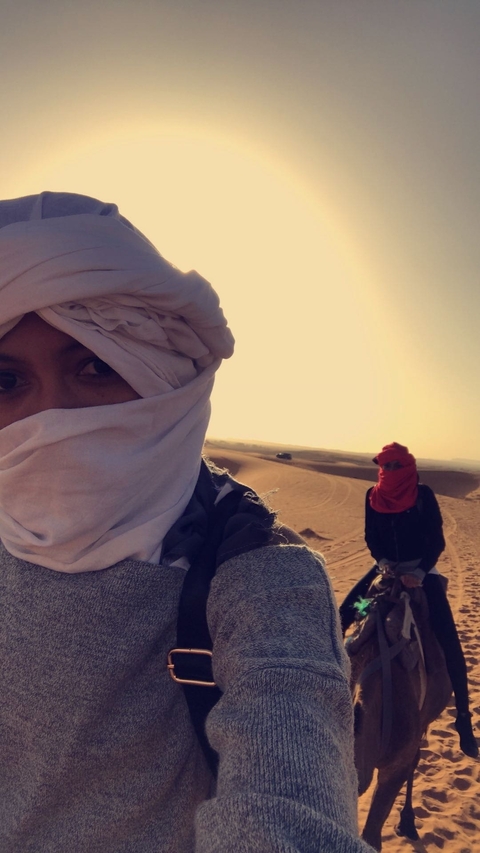       Two people wearing desert headscarves in a sandy landscape.
  