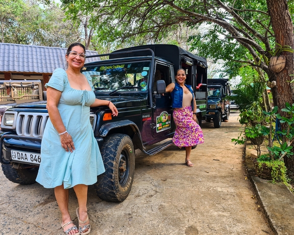 Two people posing with safari jeeps.