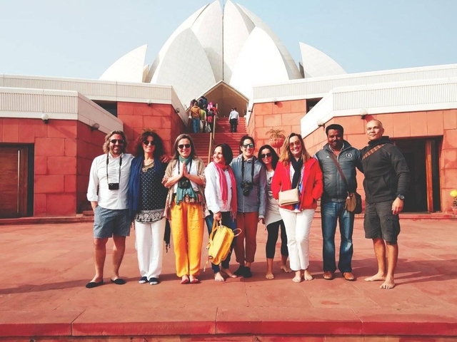 Group posing in front of a modern architectural landmark.