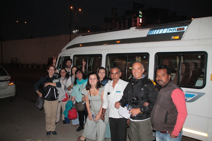 Group photo in front of a private bus at night.