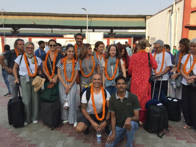 Group with luggage posing at a railway station.