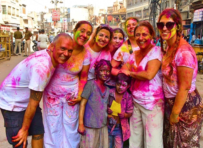 Group of people celebrating with colorful powders during a festival.