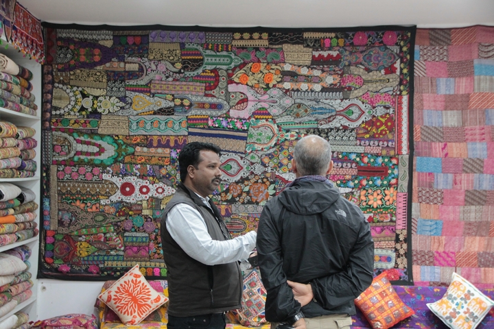 Two men in front of colorful textiles in a shop.