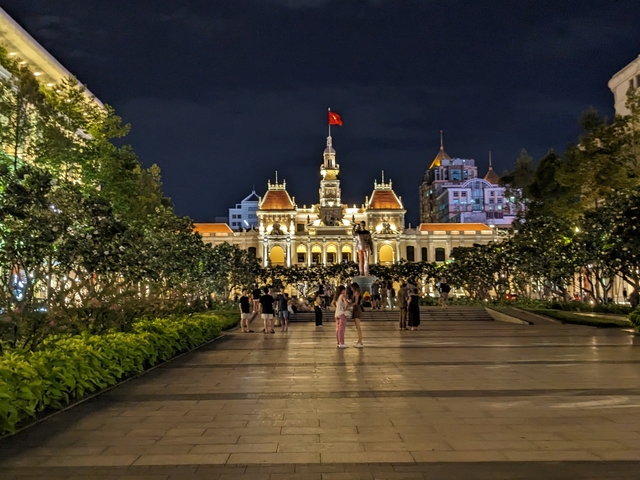 Government building illuminated at night with people walking.