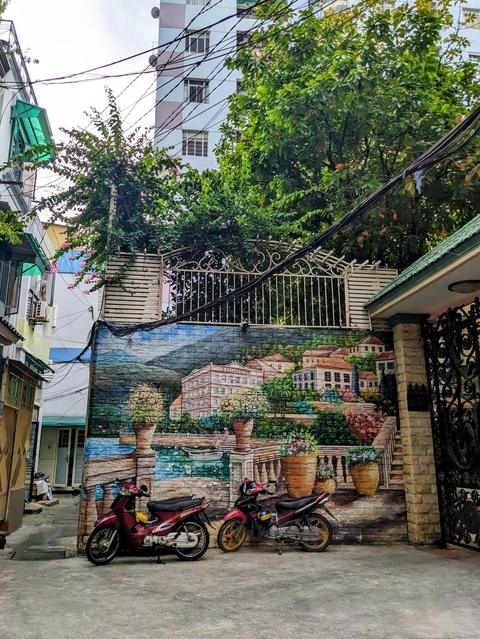      Decorated wall in an urban setting with greenery.
  