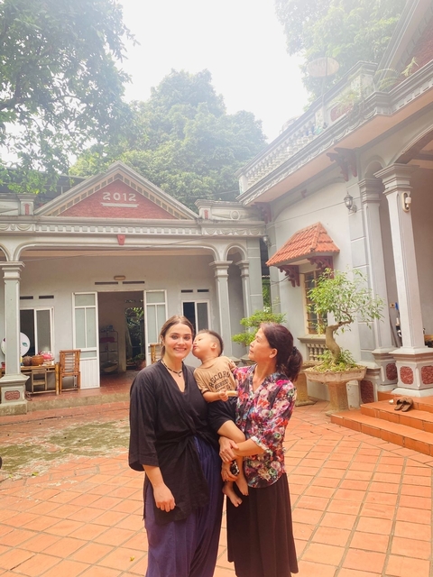       Two women and a child outside a house with the year 2012 on it.
  