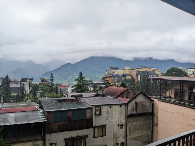       Misty city view with a grand yellow building among mountains.
  