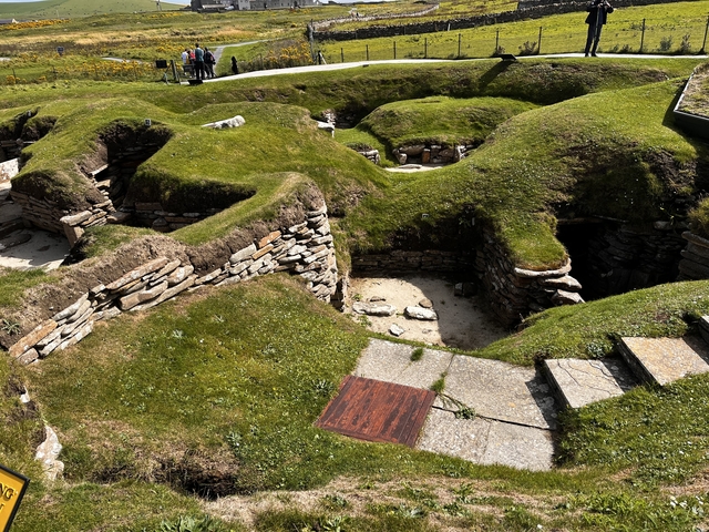 Ruins of ancient stone structures on a grassy site.