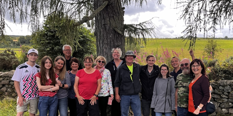Group of people posing under a large tree near a field.