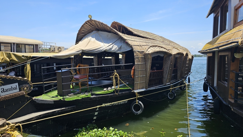 Traditional houseboats docked beside water with blue skies above.