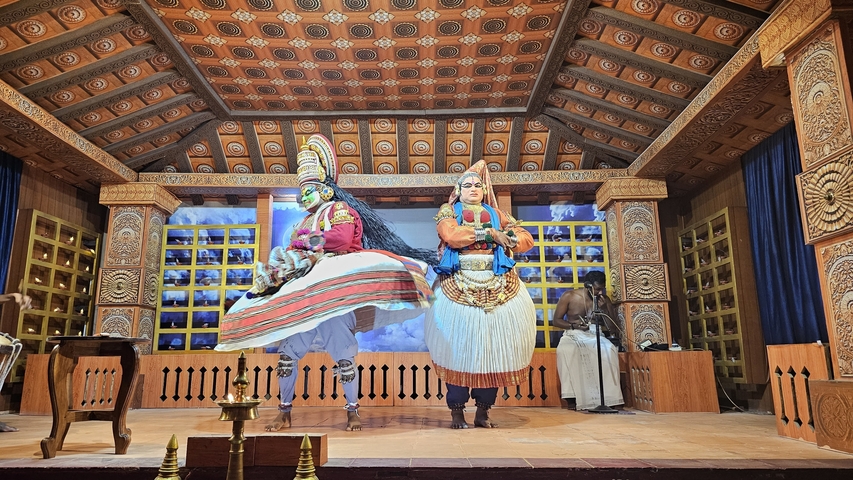 Two performers in traditional attire on a stage.