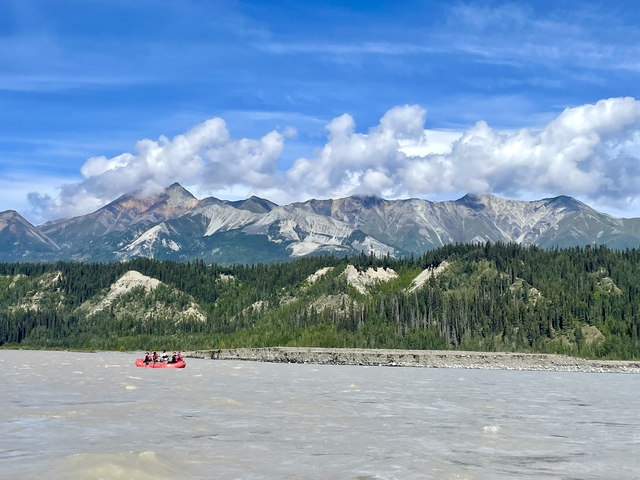       Rafting on a river with mountains in the background
  