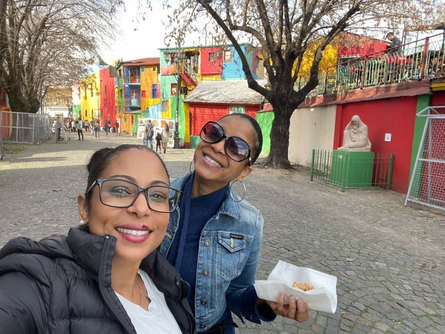       Two women posing with colorful buildings in the background
  