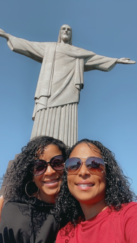 Two people in front of a large statue on a clear day