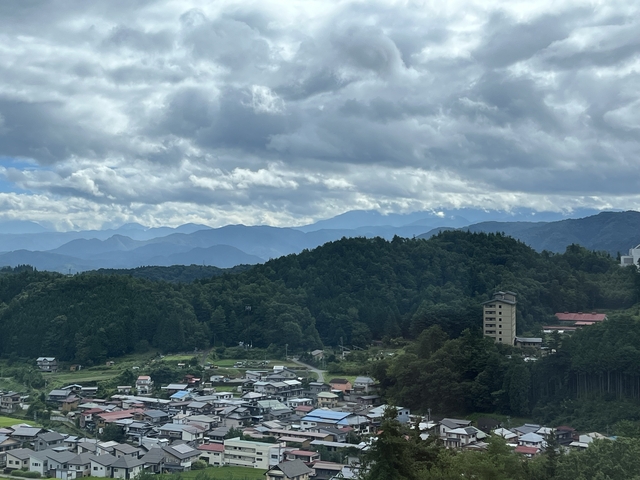       A scenic view of mountains and a town below with cloudy skies.
  