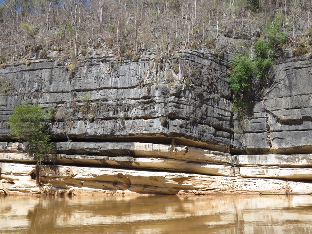       Steep cliffs with vegetation by the water.
  