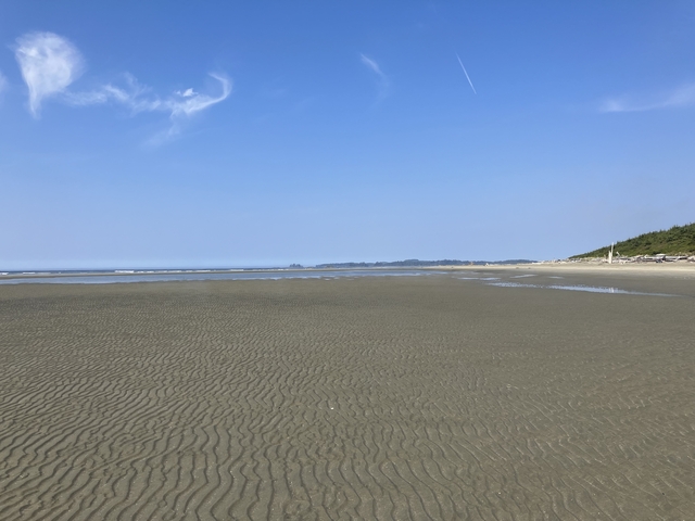 Wide sandy beach with waves in the distance.
