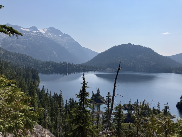       Serene mountain lake surrounded by forest and peaks.
  