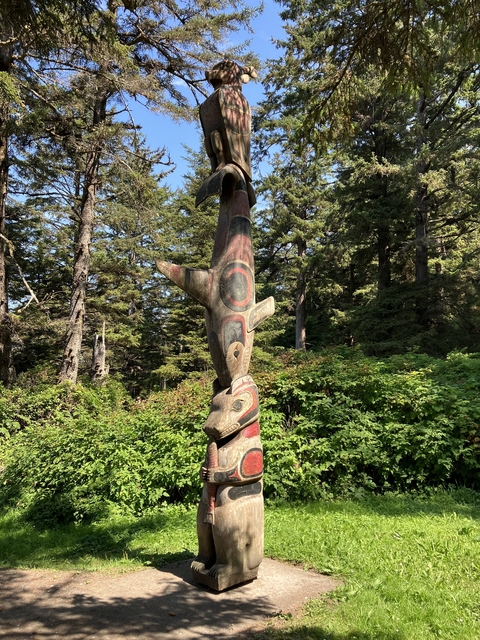       Carved totem pole in a forest setting.
  