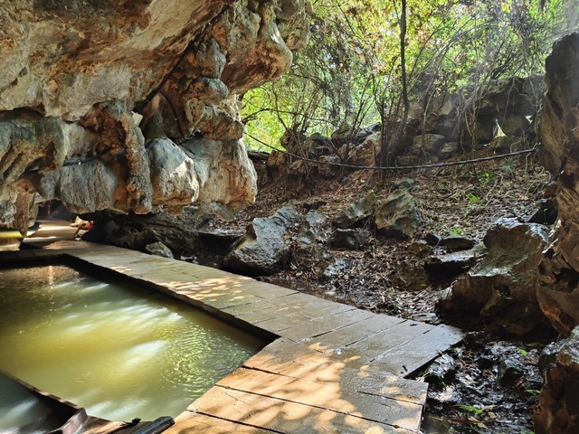 Cave entrance with water and rocky surroundings.