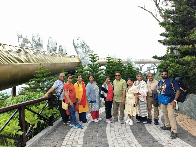 Group of people posing on a bridge with greenery around.