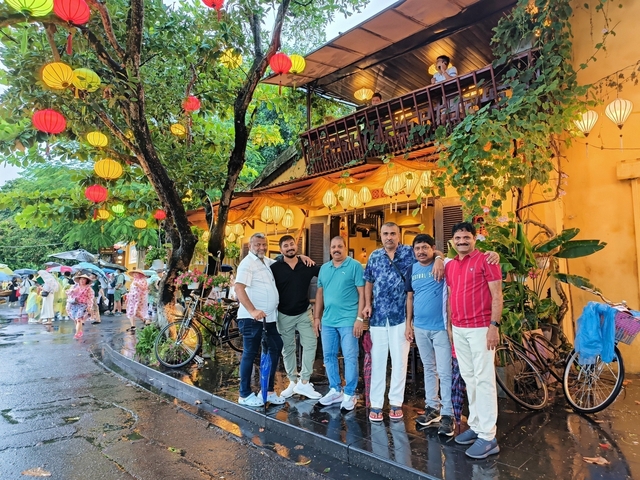 Group of people posing outside a brightly decorated building with lanterns.