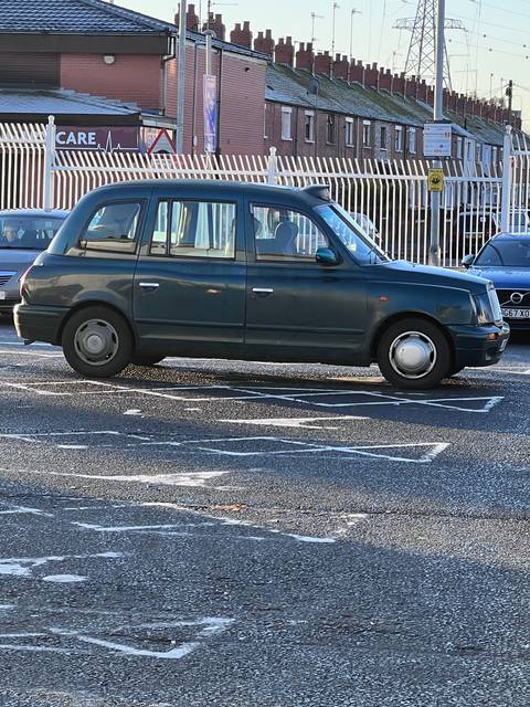 A classic black taxi on a street.