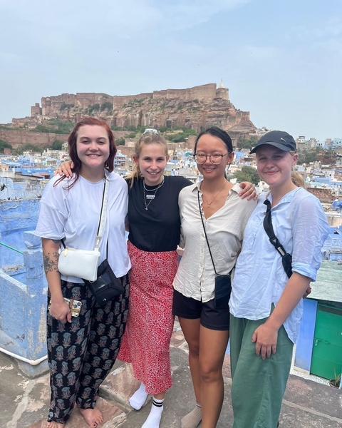 Four women posing with the blue city of Jodhpur in the background.