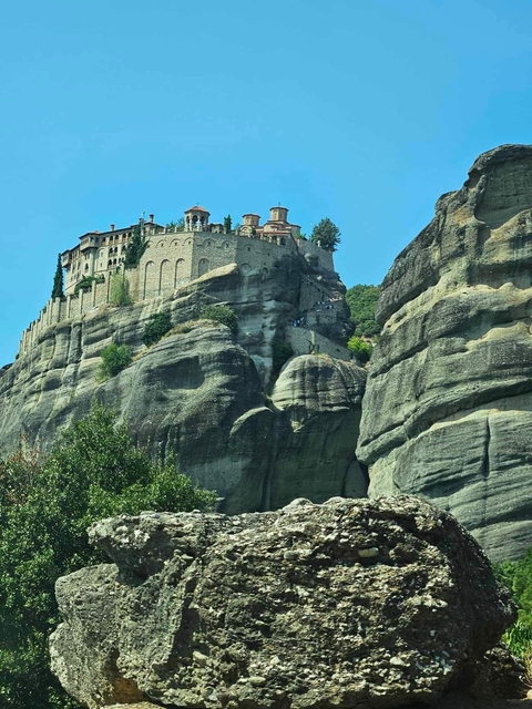       Monastery built into rocky hilltop under a blue sky.
  