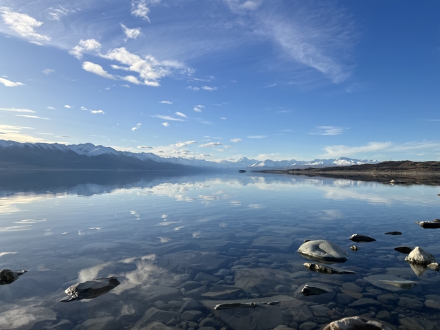 Calm lake with reflections of mountains and clear sky.