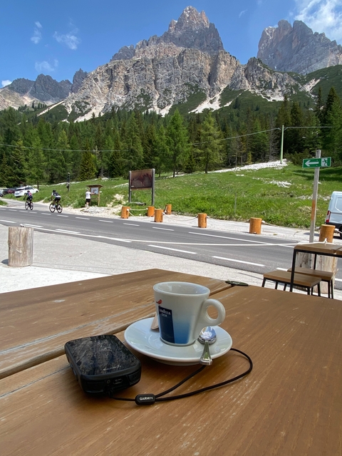       Rural road with cyclists and a coffee cup in foreground.
  