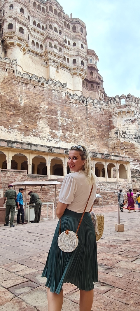       Woman posing in front of a historic building with stonework detailing.
  
